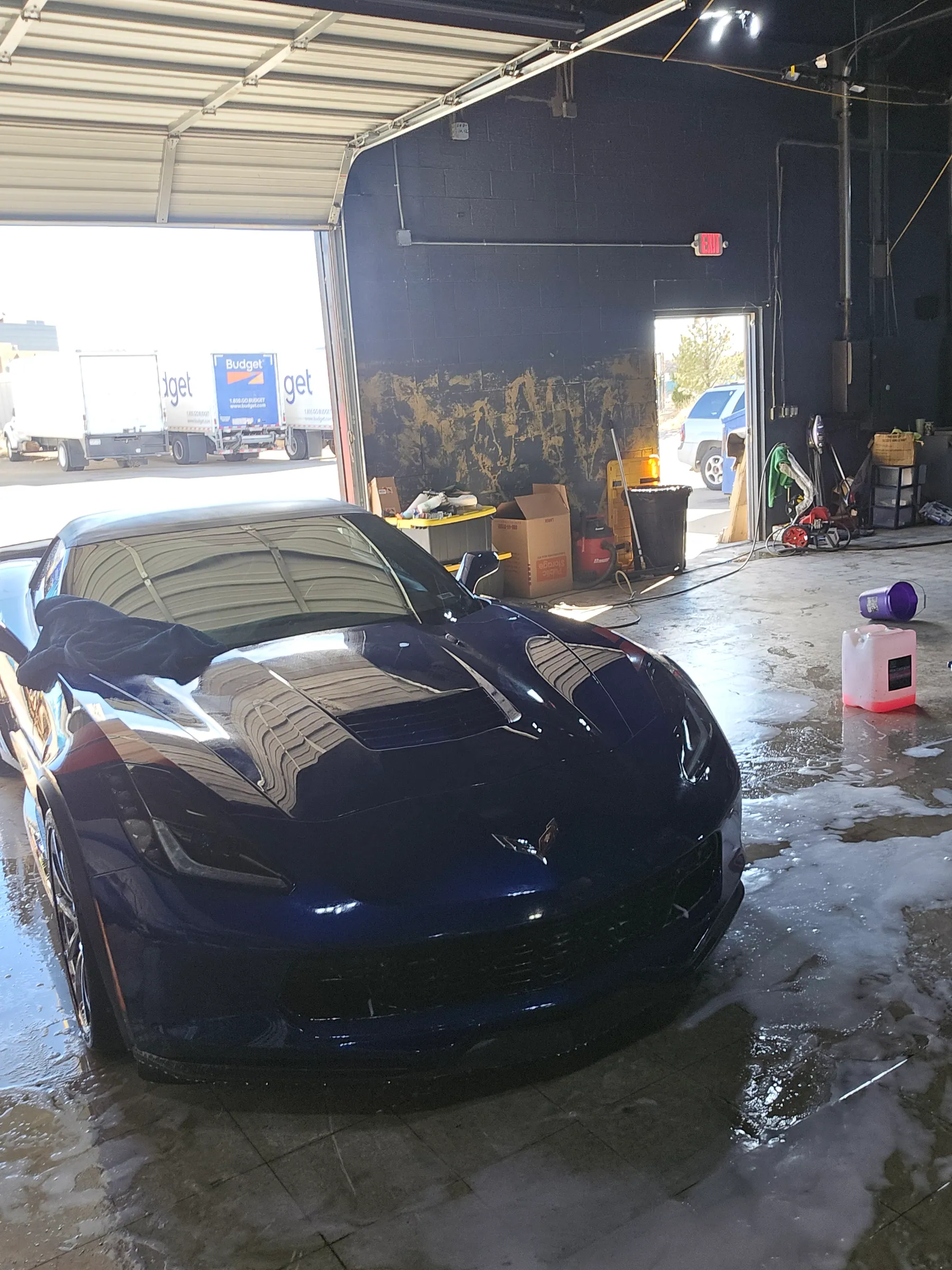 Dark blue Corvette facing the open bay inside Superior Auto Detail