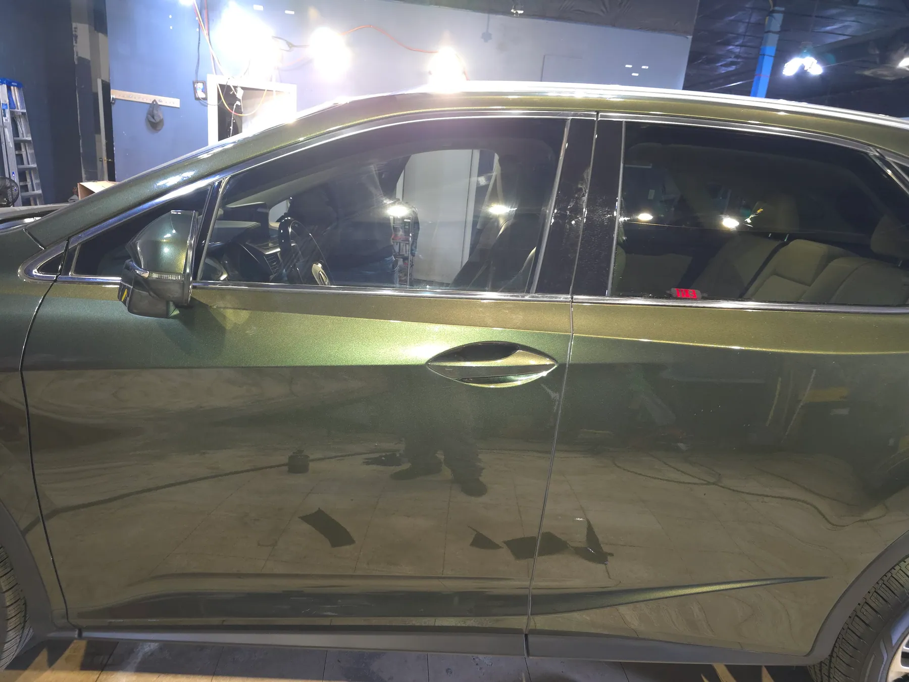 Side view of a gray sedan with dark window glass inside the shop