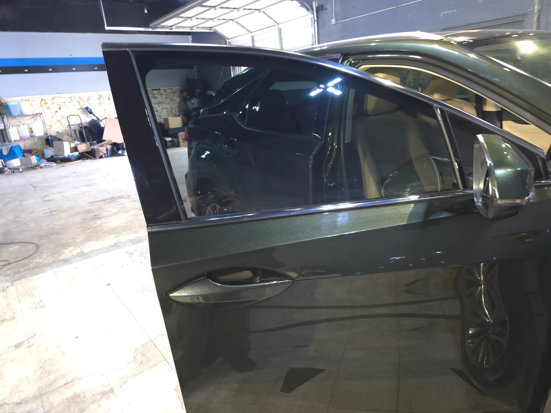 Gray sedan with an open front door and dark rear side glass in the shop